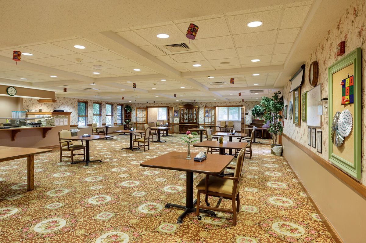 Spacious dining area with multiple tables and chairs arranged on a patterned carpet.