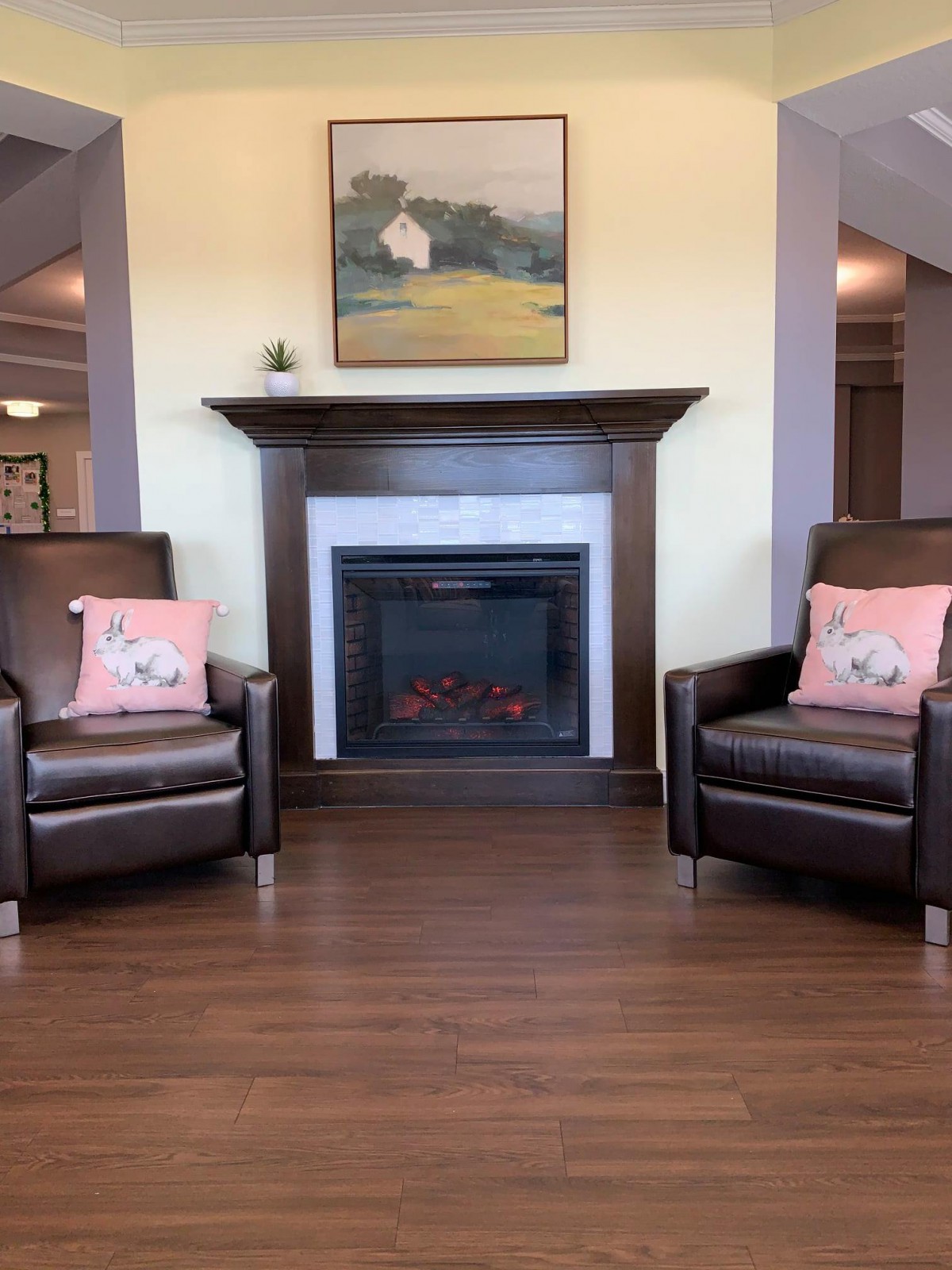 A cozy living room featuring a fireplace flanked by two leather armchairs with floral cushions.