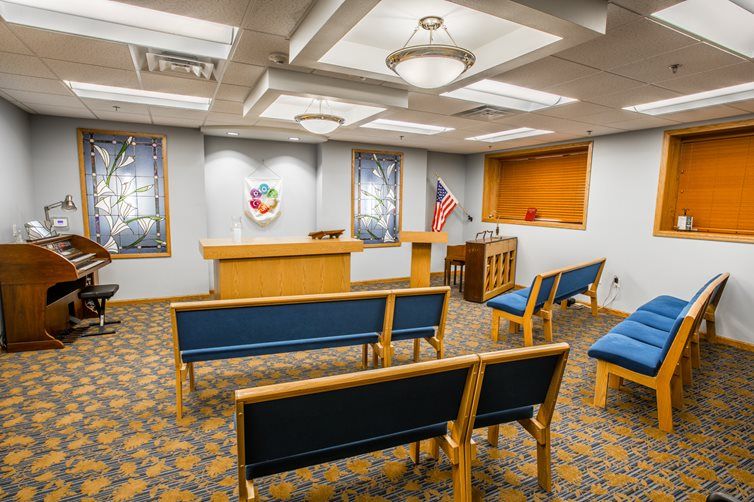 An empty courtroom with benches, a podium, and stained glass windows.