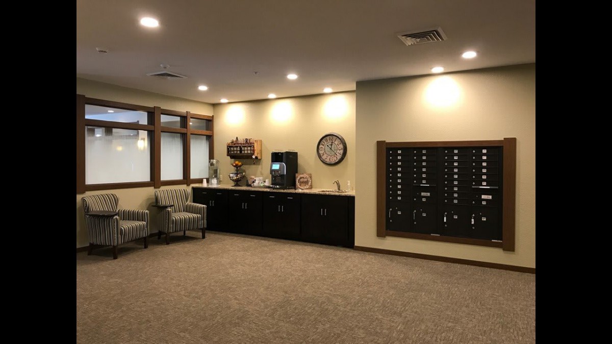 A lobby area featuring mailboxes, a coffee station, and seating arrangements.