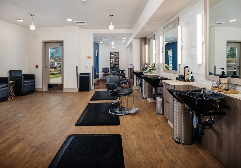 A modern hair salon interior with barber chairs, mirrors, and washing stations.