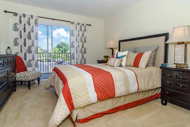 A neatly arranged bedroom with striped bedding and a view of greenery through the window.
