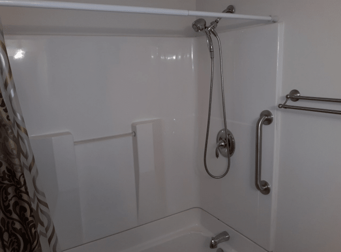 A bathroom shower area featuring a bathtub, showerhead, and grab bar.