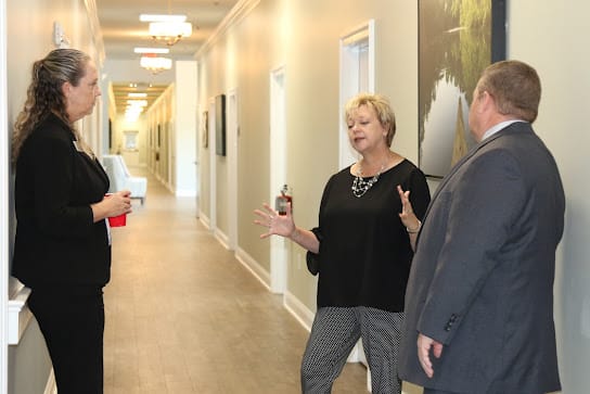 Three people engaged in a conversation in a hallway.