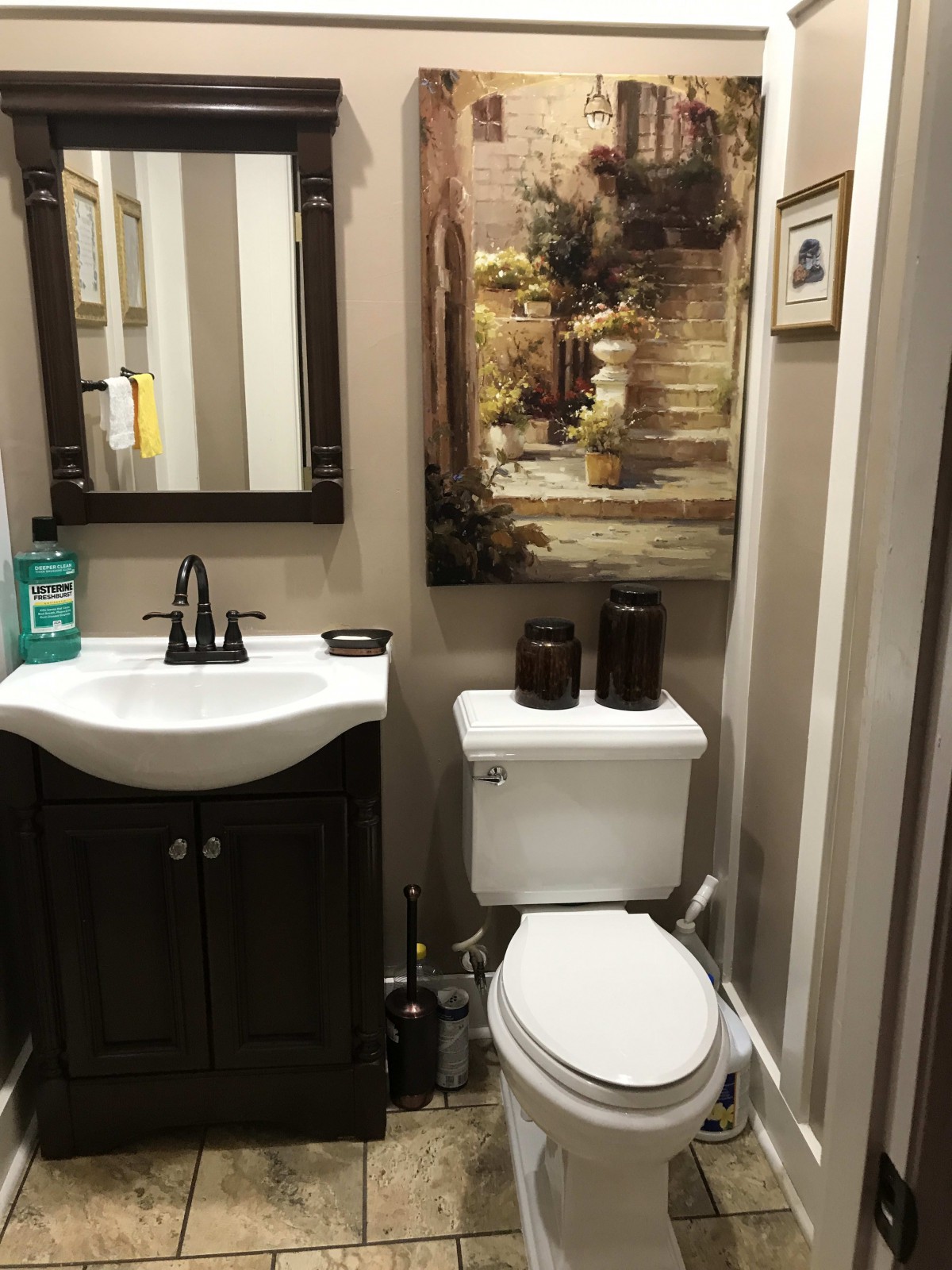 A small, well-decorated bathroom featuring a sink, toilet, and framed artwork.