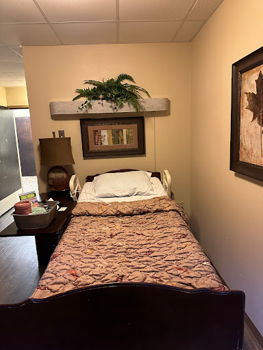 A cozy bedroom with a hospital bed, decorated with a floral bedspread and framed artwork on the walls.
