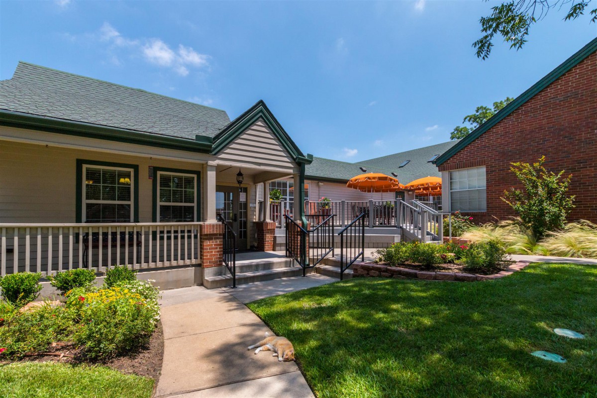 A charming house with a spacious porch and outdoor seating area, surrounded by a well-maintained lawn and garden.