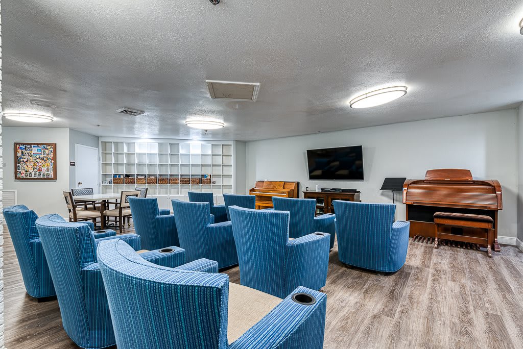 A modern lounge area with blue chairs, a television, and bookshelves.