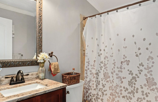 A serene bathroom space featuring a shower curtain with floral patterns, a stylish mirror, and decorative elements.