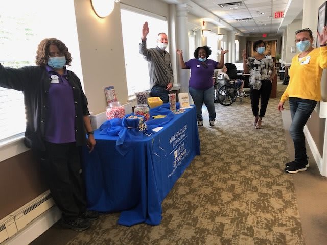 Healthcare workers standing by a table display at a community event indoors.