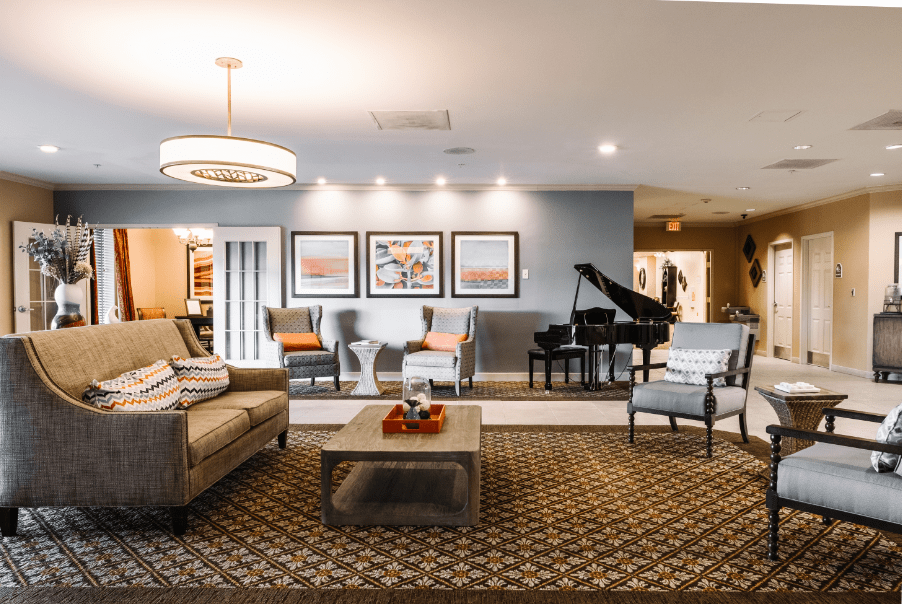 A modern living room with stylish furnishings, featuring a grand piano and framed artwork on the wall.