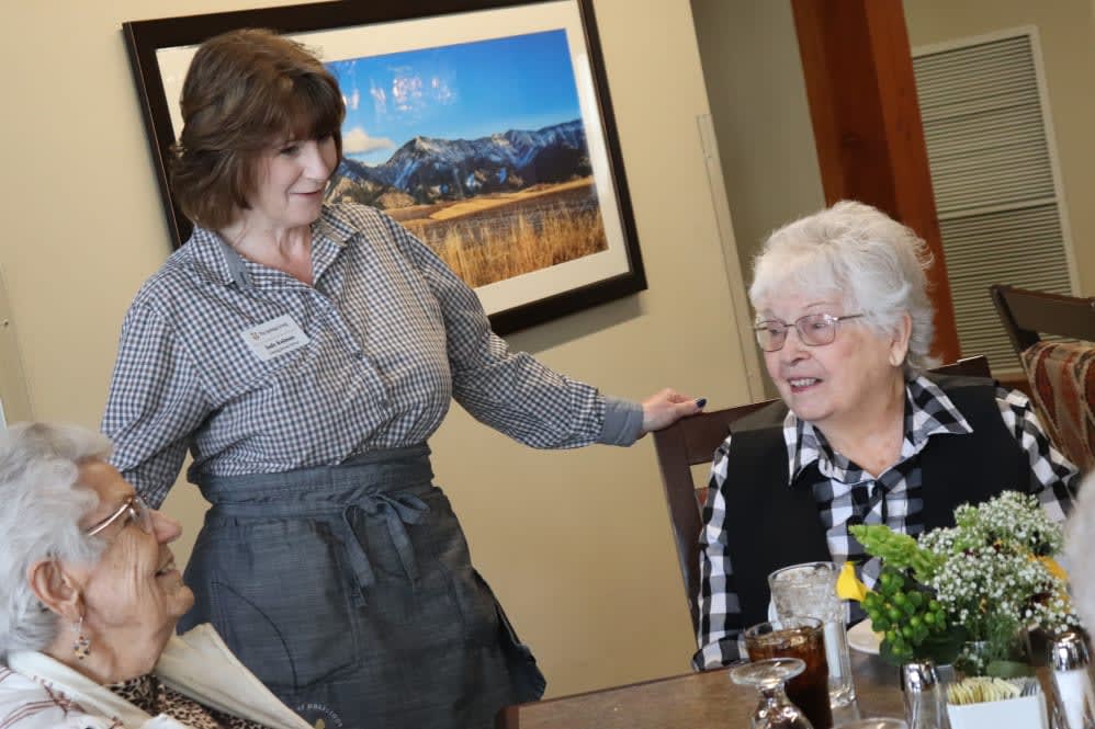 A waitress interacting with an elderly woman at a dining table.