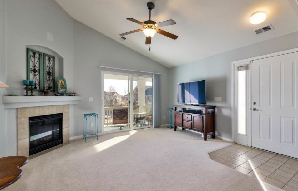 A bright living room featuring a ceiling fan, fireplace, and television.