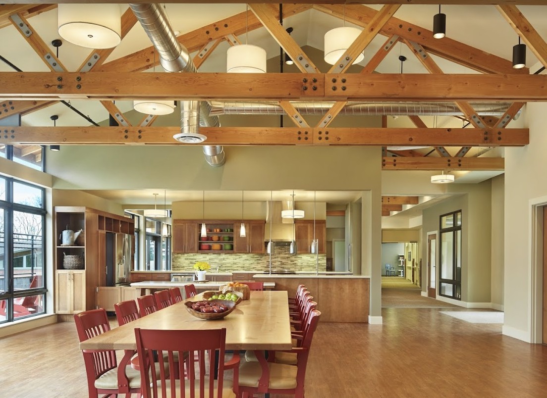 A spacious and modern dining area with exposed wooden beams and a fully equipped kitchen.