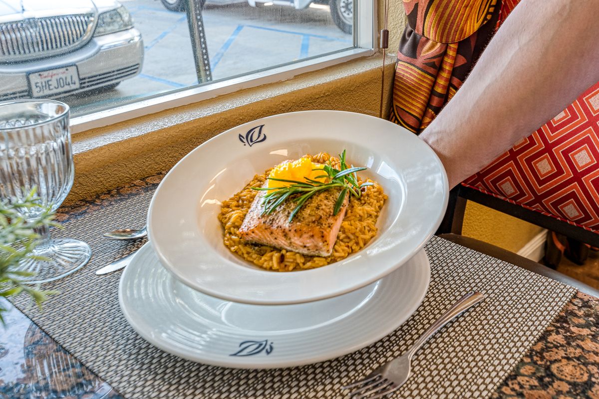 A beautifully presented salmon dish served on a bed of risotto at a restaurant.