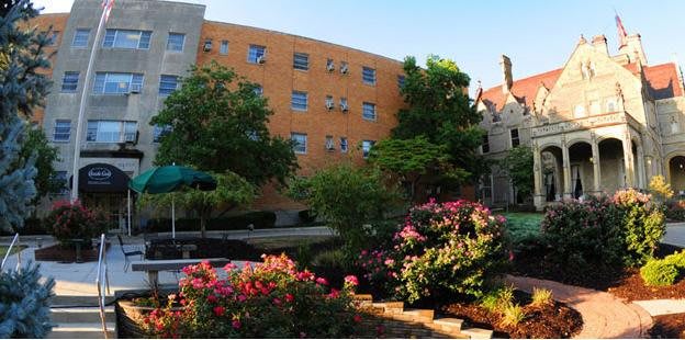 A vibrant garden with colorful flowers in front of a modern building under a clear blue sky.