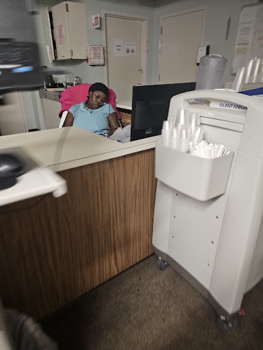 A person seated at a reception desk, working on a computer in an office environment.