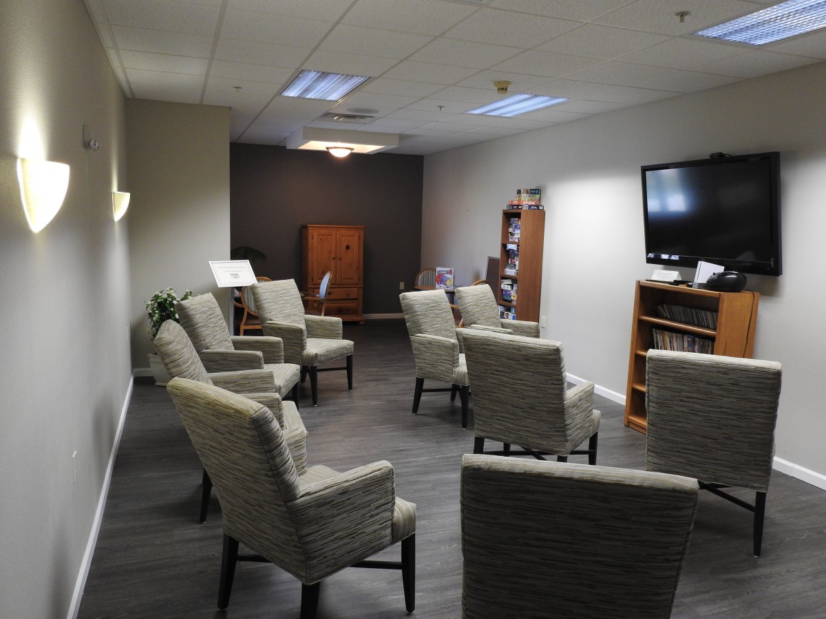 A waiting room with arranged chairs, a television, and a bookshelf.