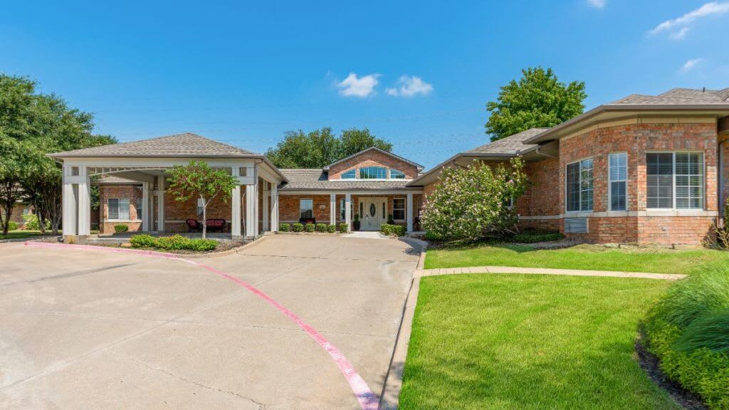 A sunny day at a residential building with a driveway and well-maintained lawn.