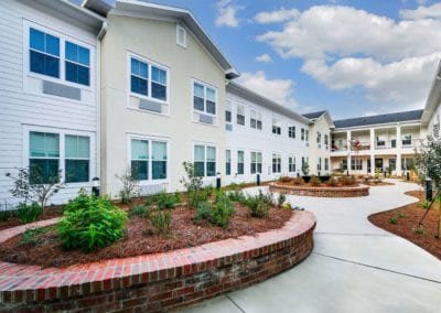A modern residential building with well-maintained landscaping and a clear sky above.