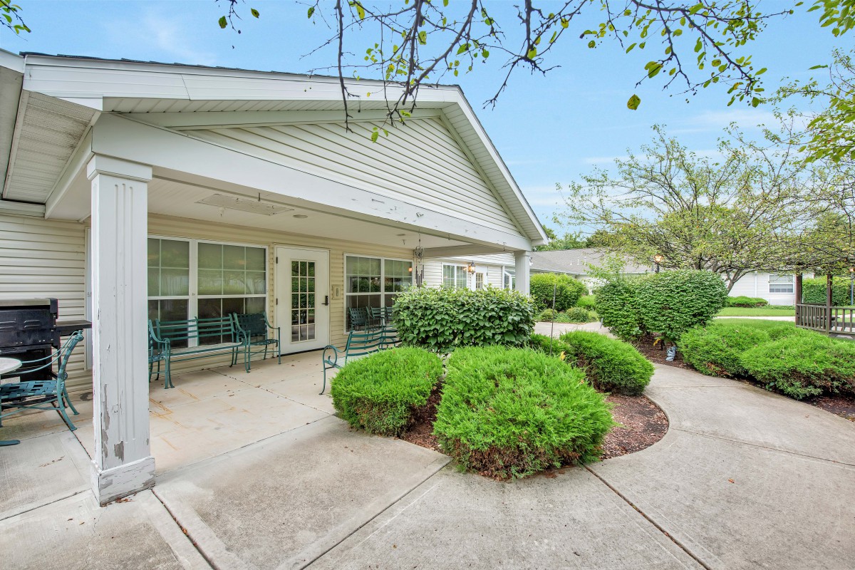 A peaceful backyard patio with neatly trimmed shrubs and outdoor seating.