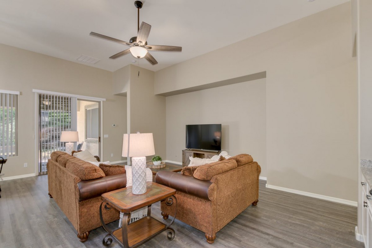 A cozy living room with sofas, a television, and a ceiling fan.