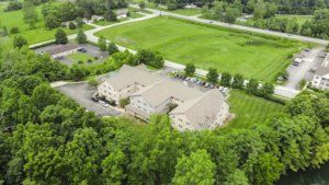 Aerial view of a building surrounded by greenery and roads.