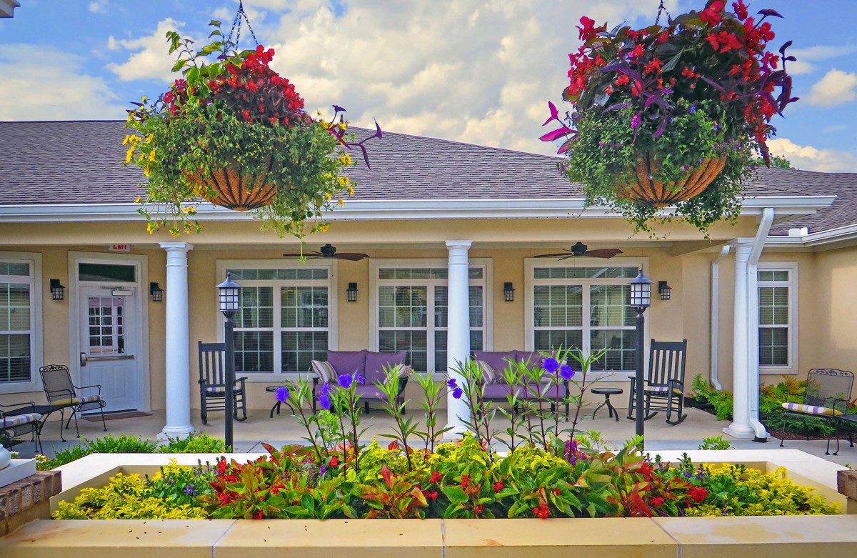 A charming house with a landscaped garden and hanging plants on the porch.