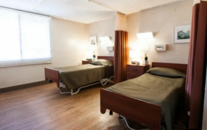 A clean and organized hospital room with two beds and a curtain divider.