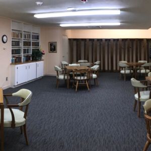 A well-lit indoor meeting room with several tables and chairs.