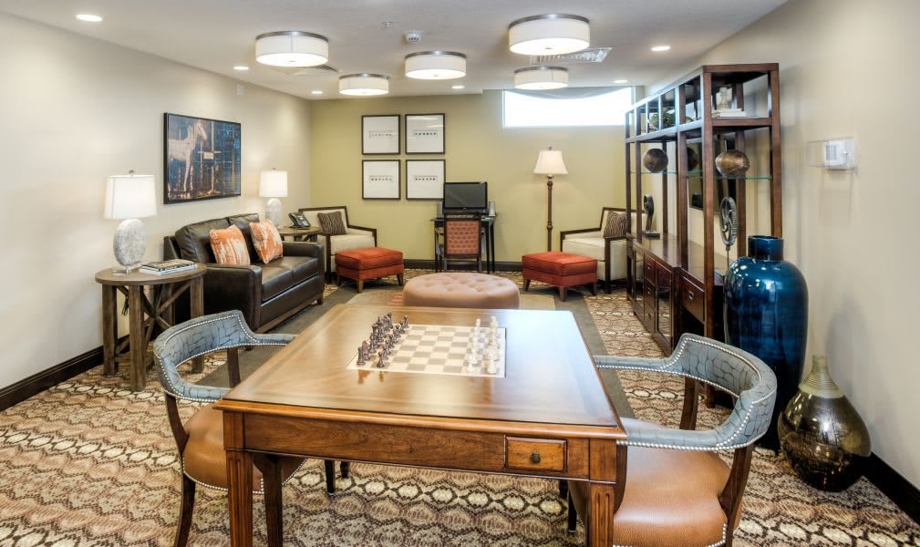 A cozy living room with a chess table and seating area.