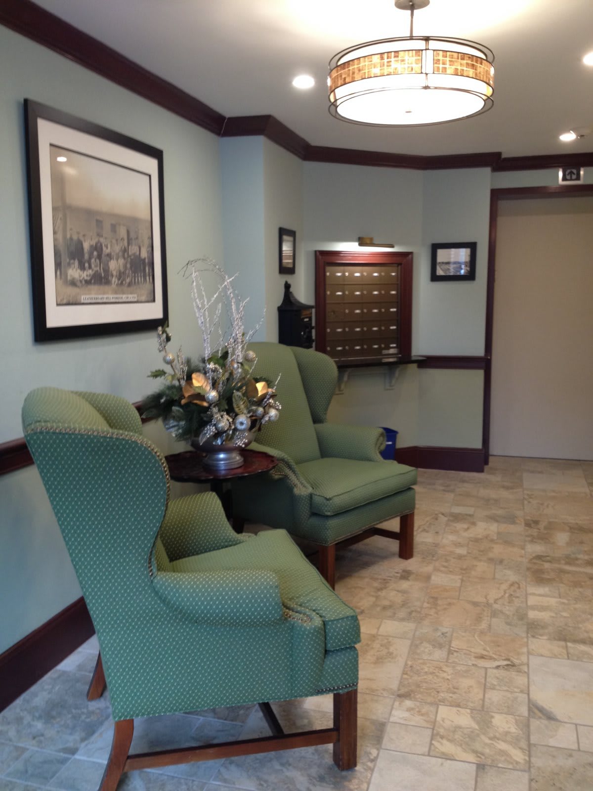 A cozy lobby with green chairs and floral decoration.