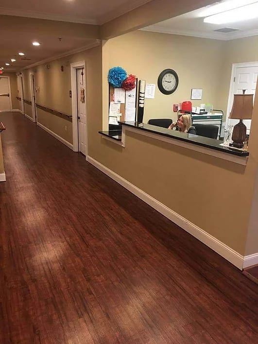 A long hallway with a reception desk and wooden flooring.