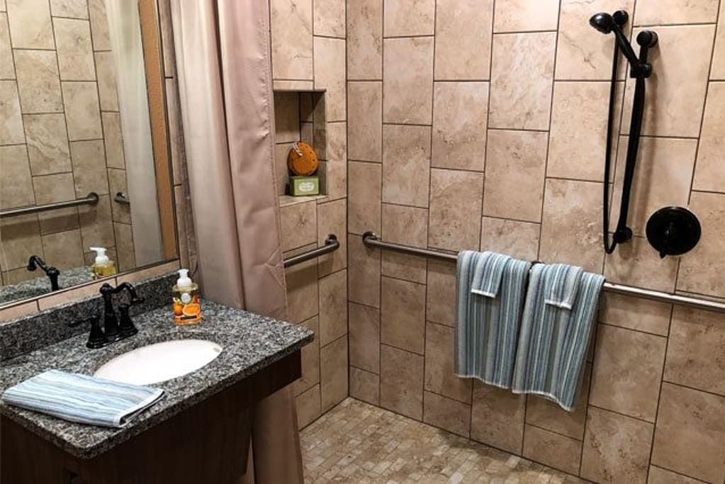 A modern bathroom with tiled walls, a granite countertop, and neatly hung blue-striped towels.