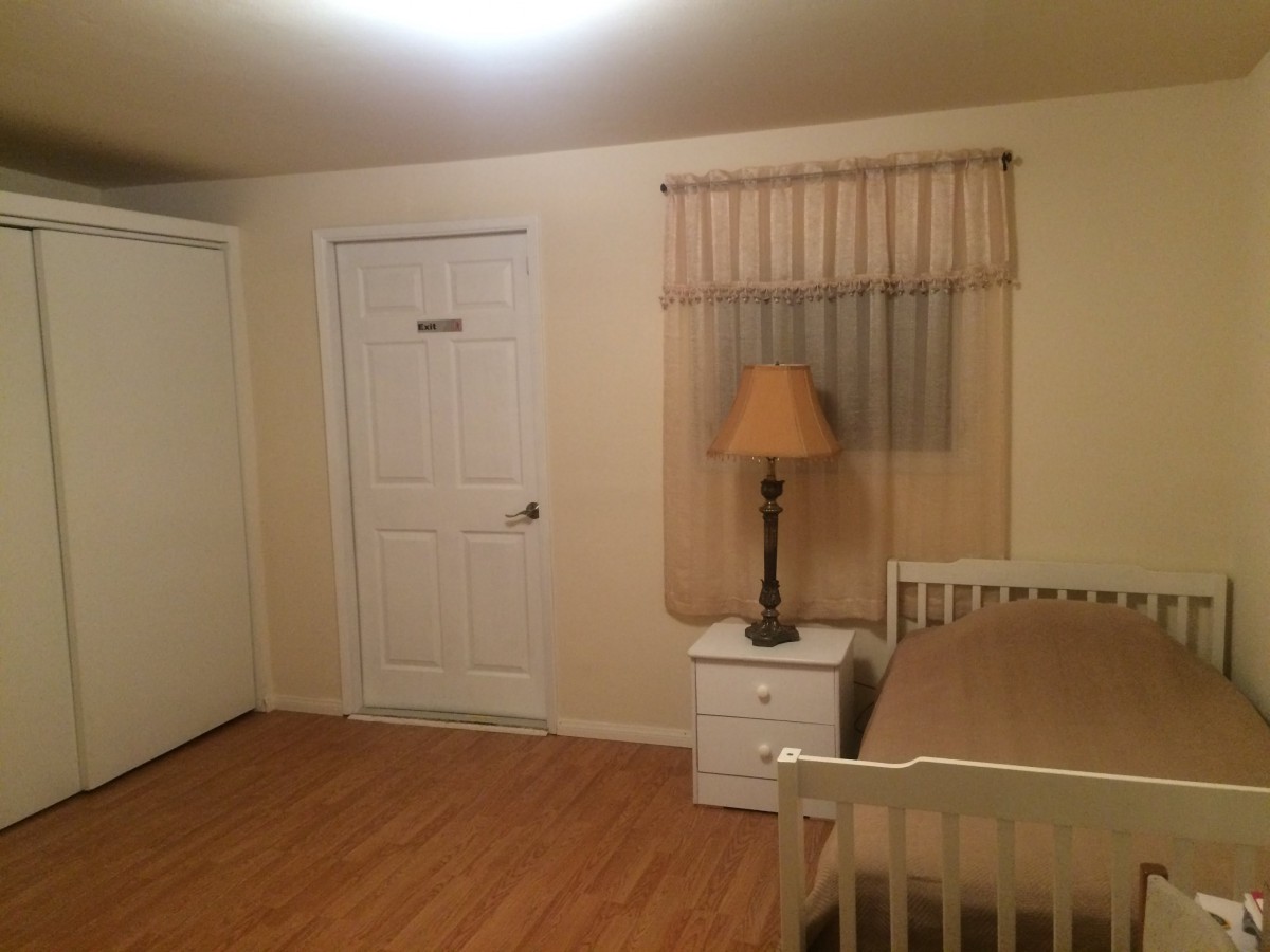 A simple bedroom with a bed, nightstand, and lamp.