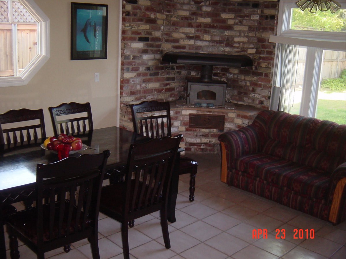 A cozy living and dining area featuring a brick fireplace, dining table with chairs, and a comfortable couch.