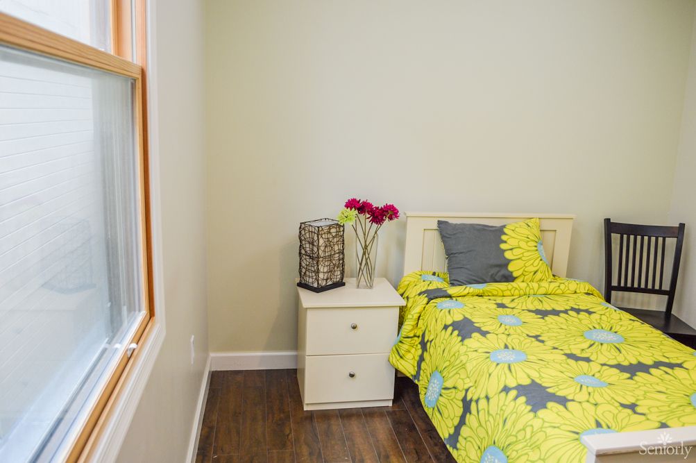 A cozy bedroom with a vibrant bedspread, nightstand, and decorative flowers.