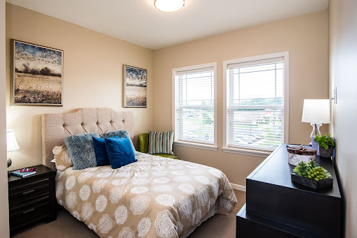 A cozy and well-decorated bedroom featuring a comfortable bed, stylish pillows, and natural light coming through the windows.