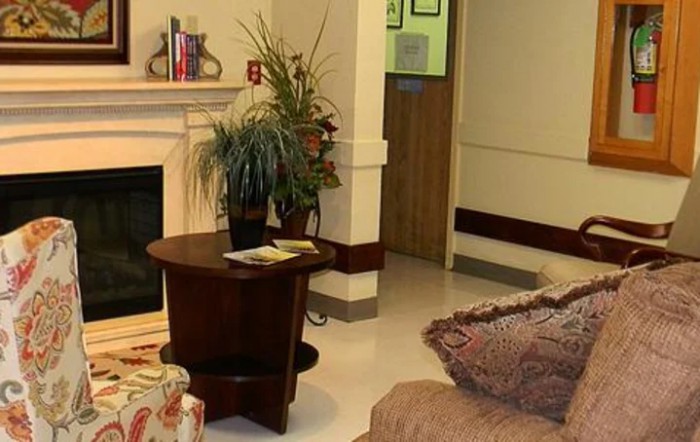 A cozy living room with a fireplace, plants, and comfortable seating.
