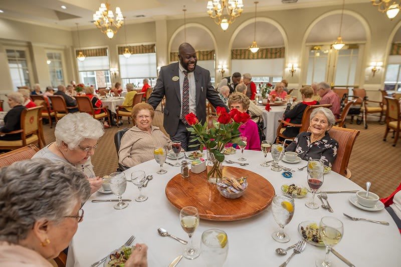 A group of seniors enjoying a formal dining experience with lively conversation.