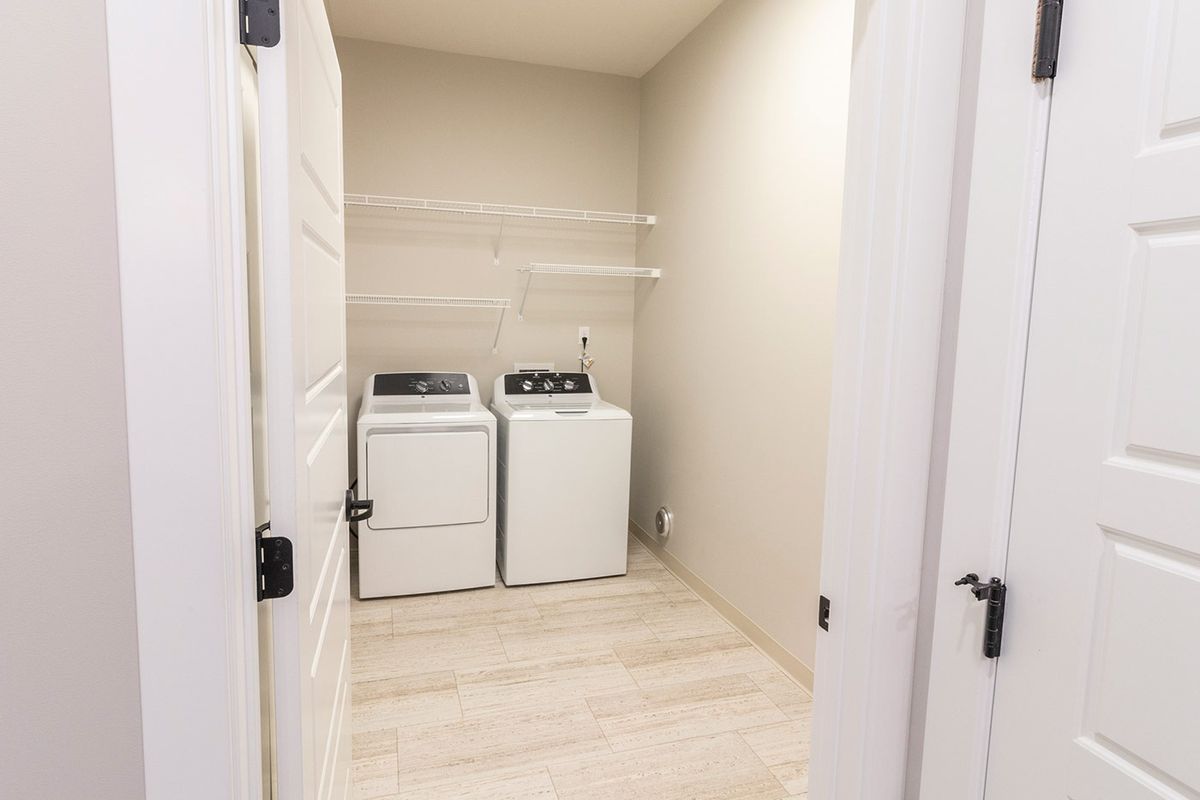 A simple laundry room with a washer, dryer, and shelving.