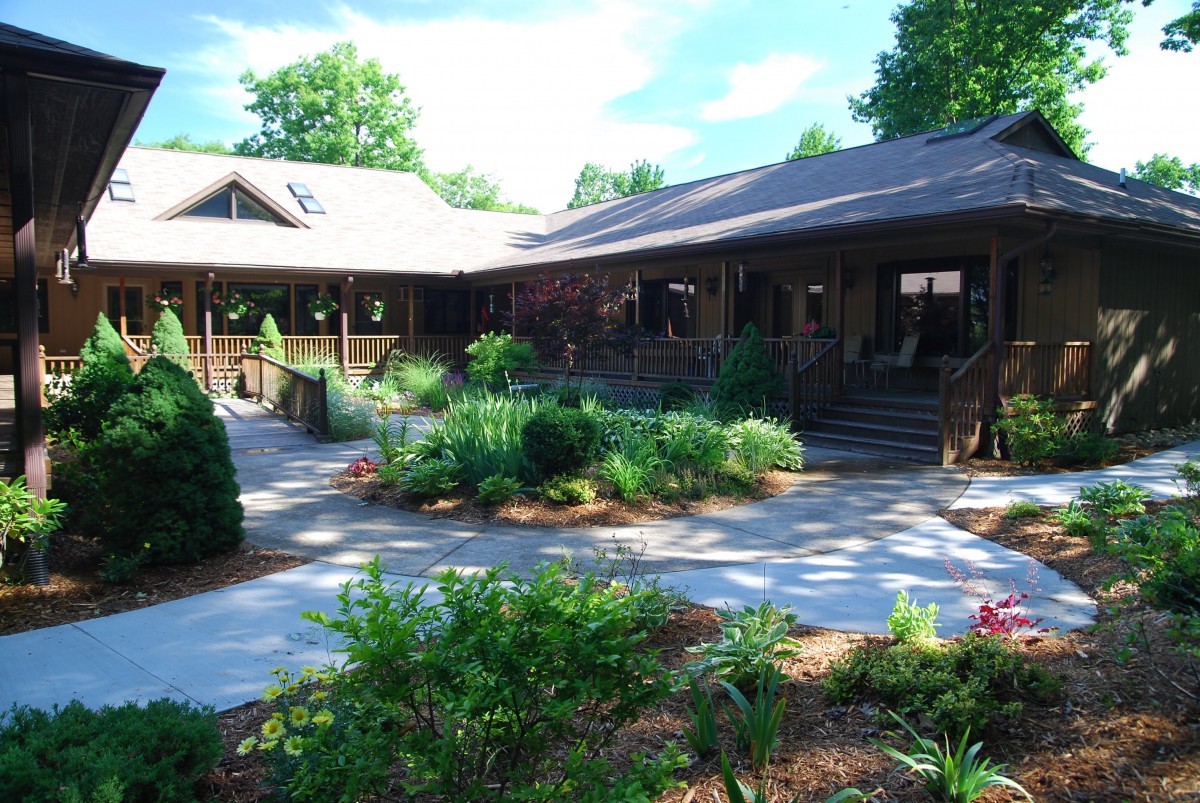 A serene outdoor garden with pathways surrounded by greenery and a modern building.