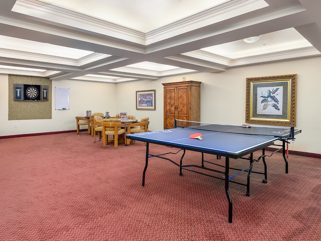 A recreational room featuring a ping pong table and a dining area.