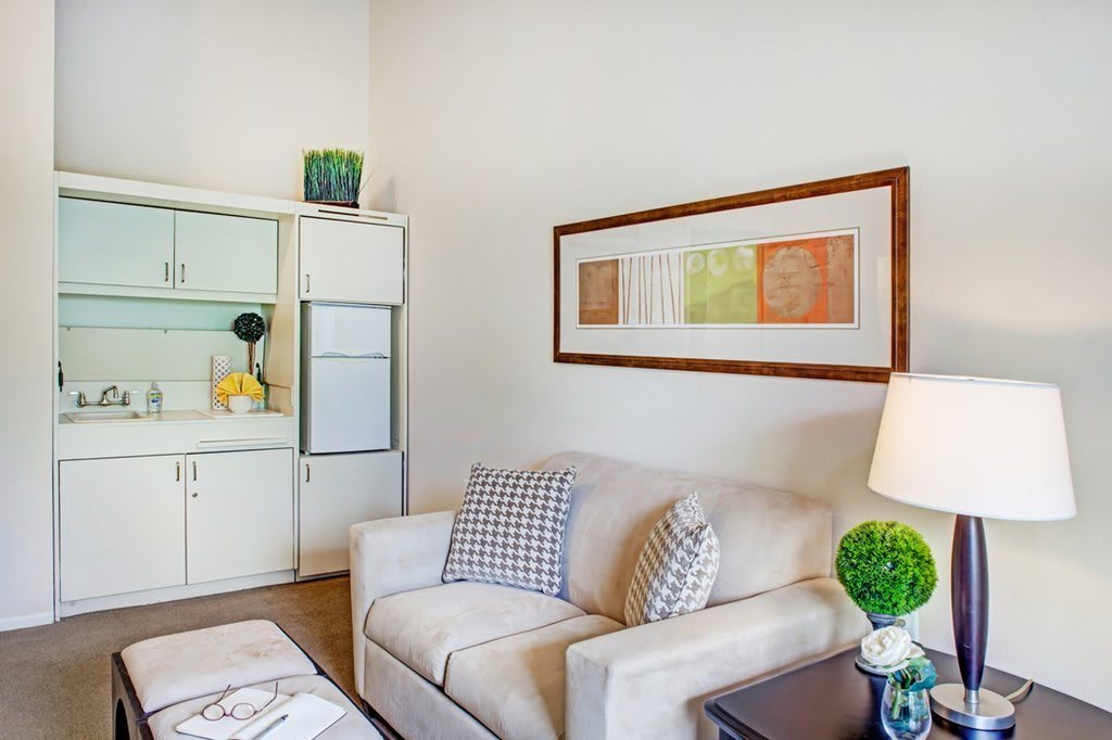 A cozy living room with a beige couch, decorative pillows, and framed artwork on the wall.