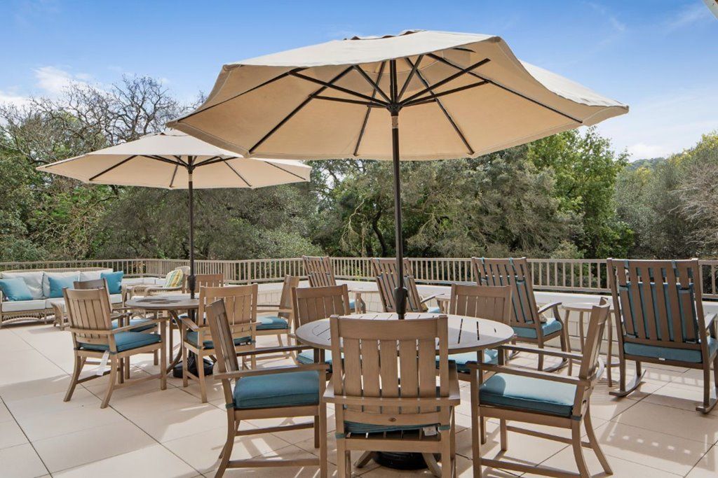 A sunny outdoor patio with tables, chairs, and umbrellas set up on a deck.