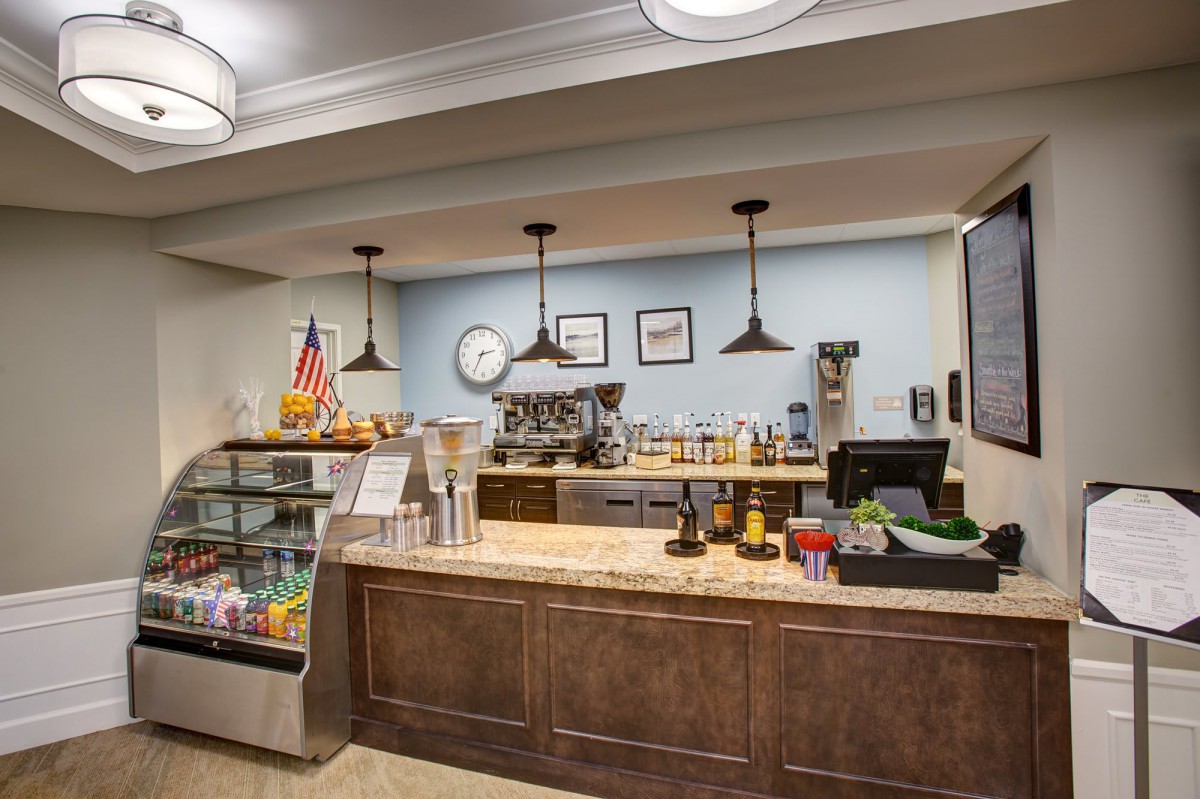 A cozy coffee shop with a well-organized counter featuring an espresso machine, pastry display, and menu board.