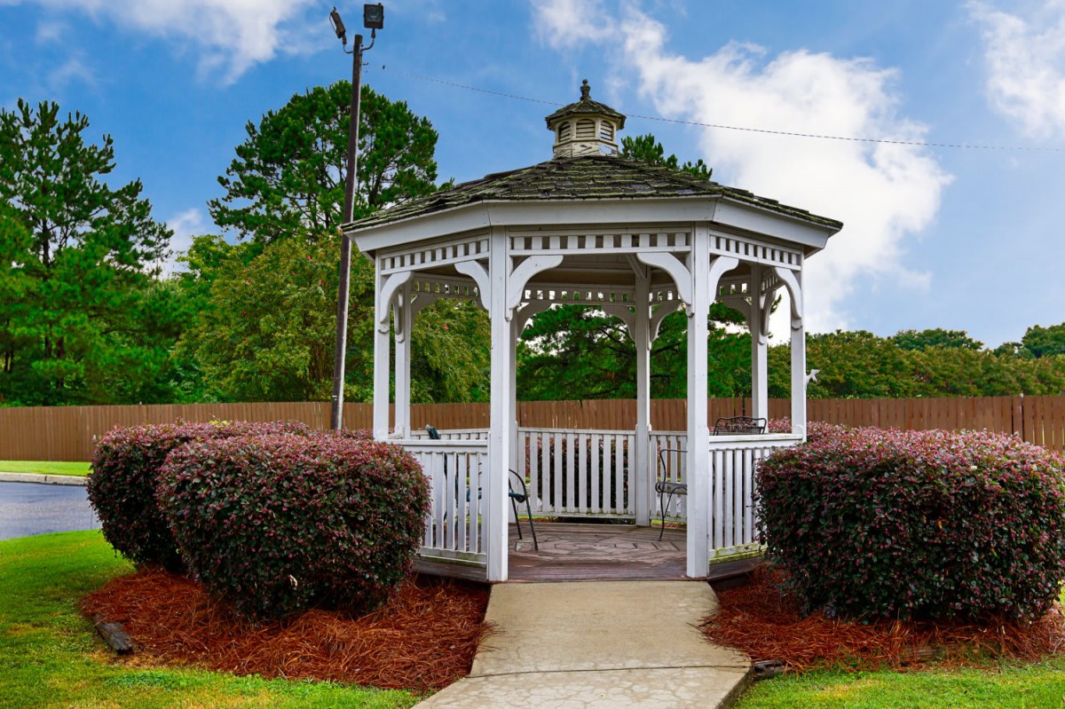 A quaint white gazebo surrounded by lush greenery in a peaceful park setting.