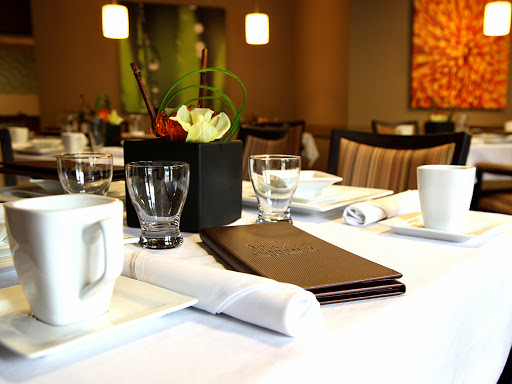 A neatly arranged dining table featuring a menu, glassware, and a decorative centerpiece.