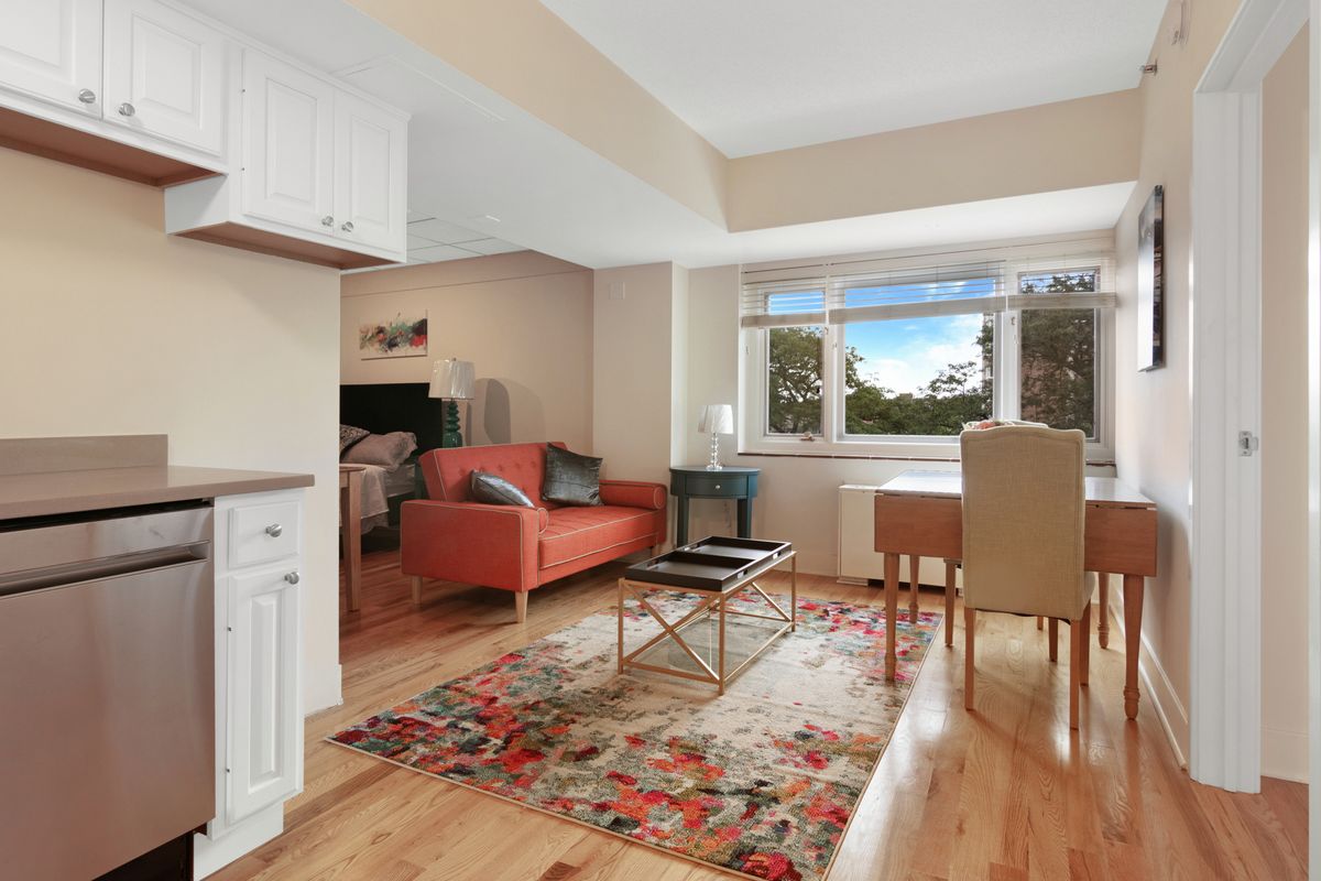 A cozy open-plan living space with a sofa, dining table, and kitchen area, featuring a large window with a scenic view.