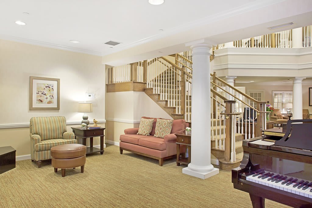 A cozy living room with a staircase, sofa, and tables.